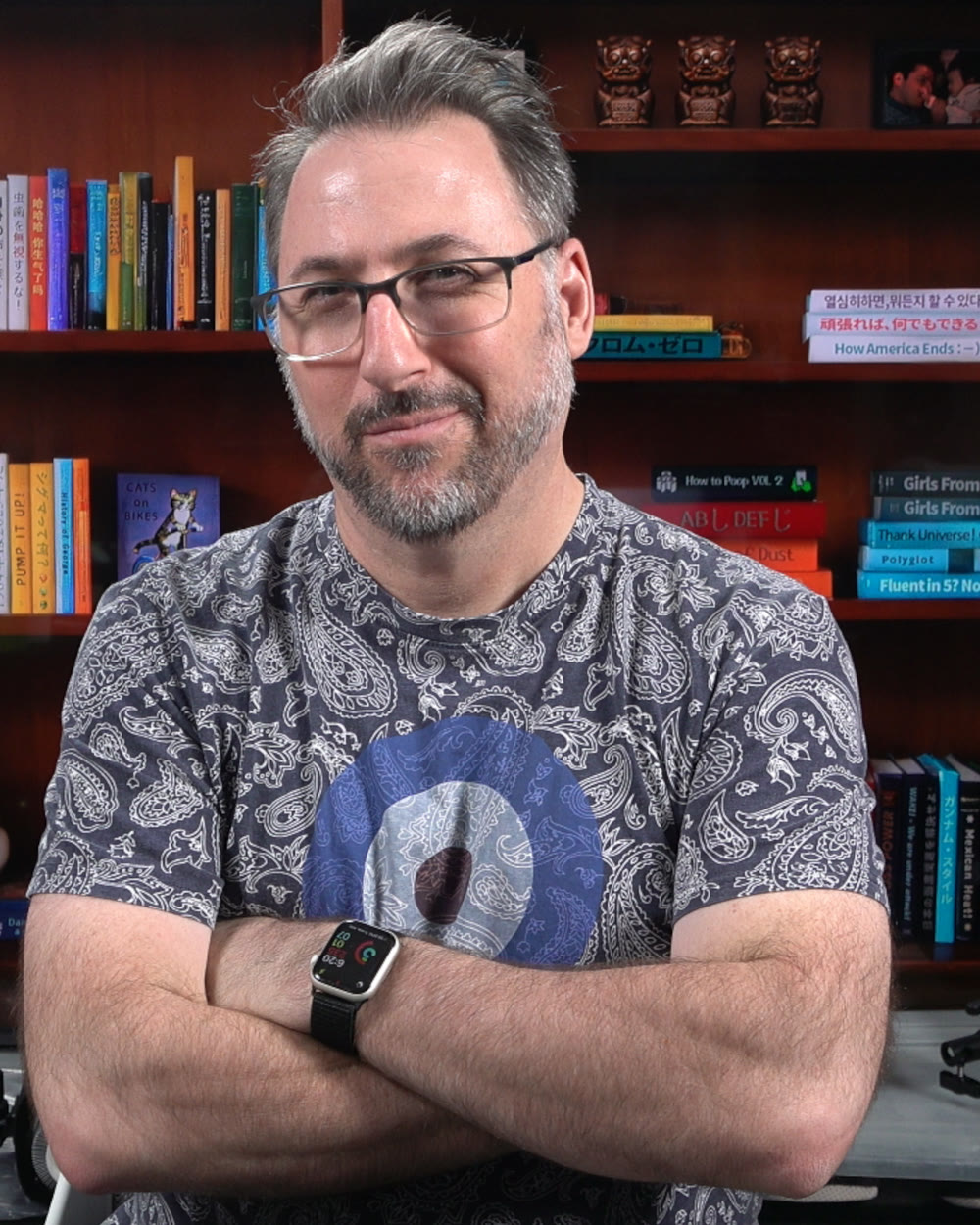 George Trombley, arms folded, standing in front of a bookshelf.